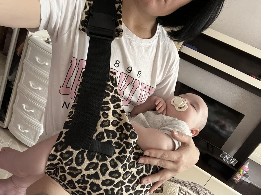 Bebê no colo usando o carregador estampado